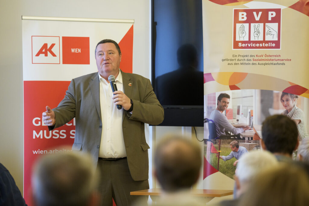 Ein Mann, Vizepräsident Helmut Gruber von der AK Wien, spricht vor einer Gruppe Menschen in ein Mikrofon.