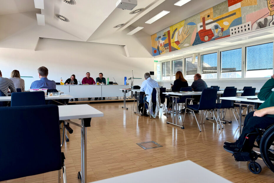 BVP Vernetzungstreffen Tirol Seminarraum In einem Seminarraum sitzen einige Menschen an Tischen, vorne am Pult sitzen drei Personen
